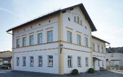 Das Bild zeigt die als Bürgerhaus genutzte alte Schule im Zentrum des Ortsteils Niedergottsau. Vor dem Bürgerhaus ist der Maibaum zu sehen.